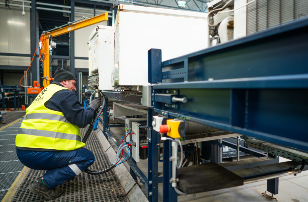 Pracownik firmy Terra Recycling podczas procesu recyclingu lodówki przy maszynie